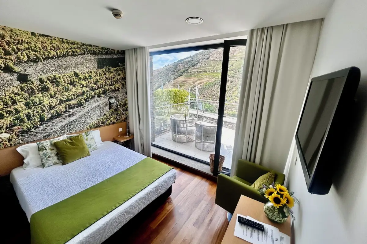 Guest room at LBV House Hotel with a balcony overlooking terraced Douro vineyards.