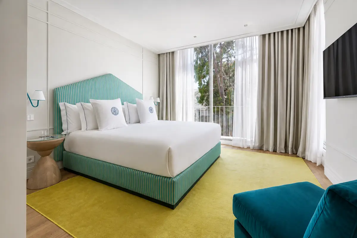Bright room at One Shot Palácio Cedofeita in Porto with a turquoise bed.