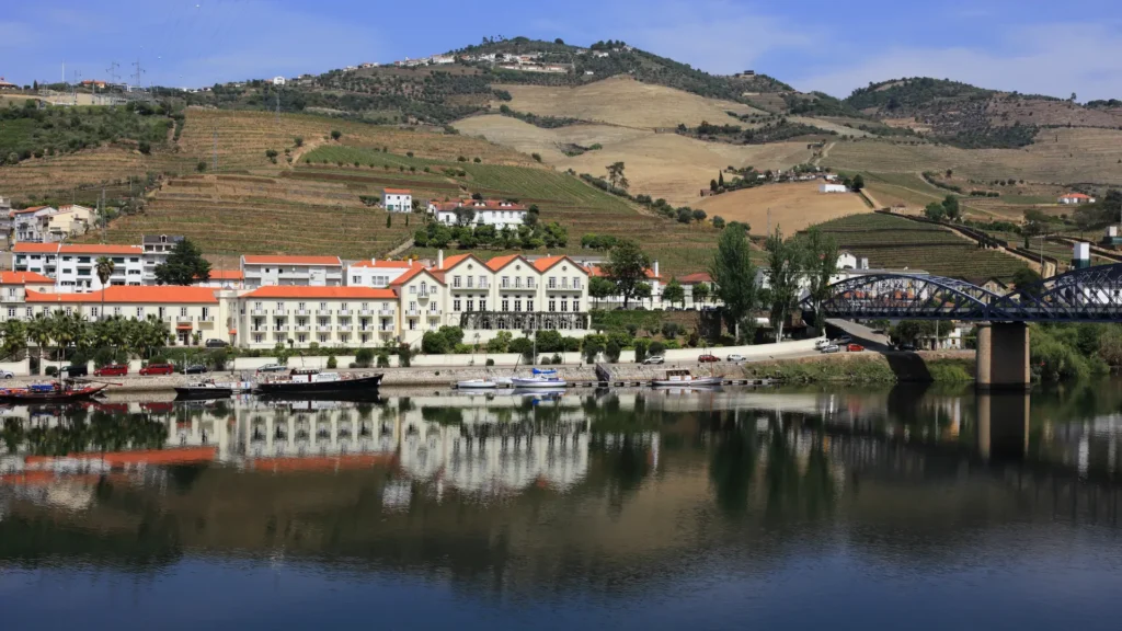 Pinhão waterfront and bridge along the Douro River with vineyard-covered hills.