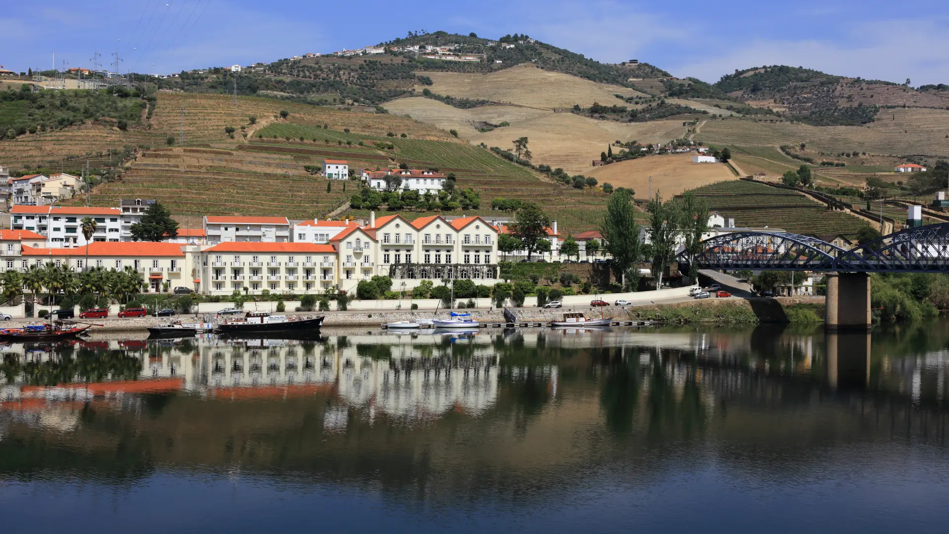 Pinhão waterfront and bridge along the Douro River with vineyard-covered hills.