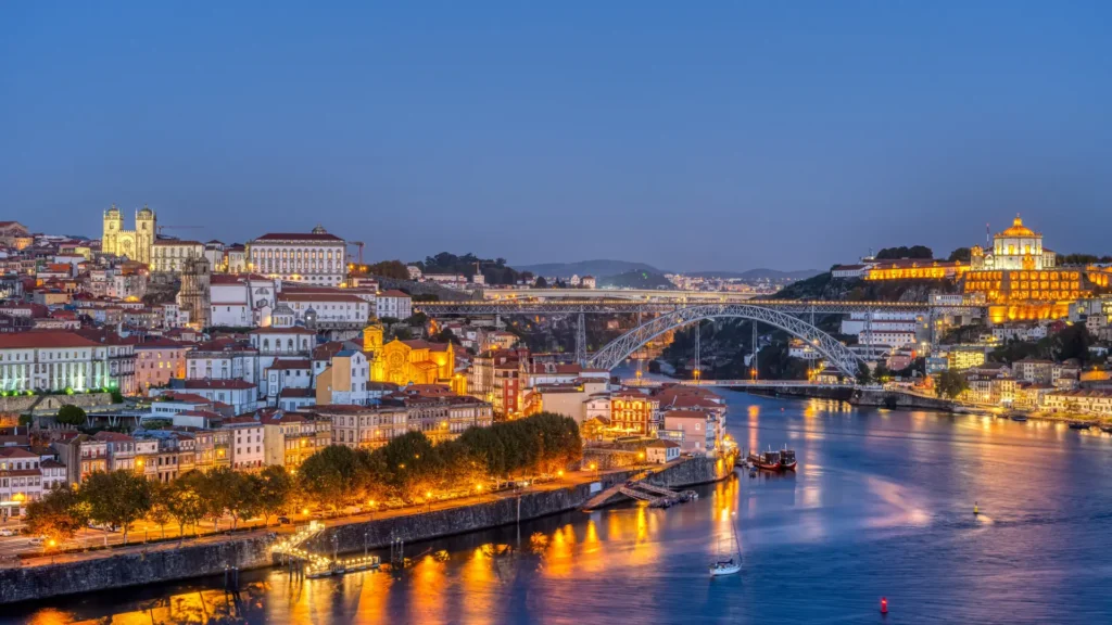 Dom Luís I Bridge over the Douro River with Porto and Vila Nova de Gaia illuminated at night.