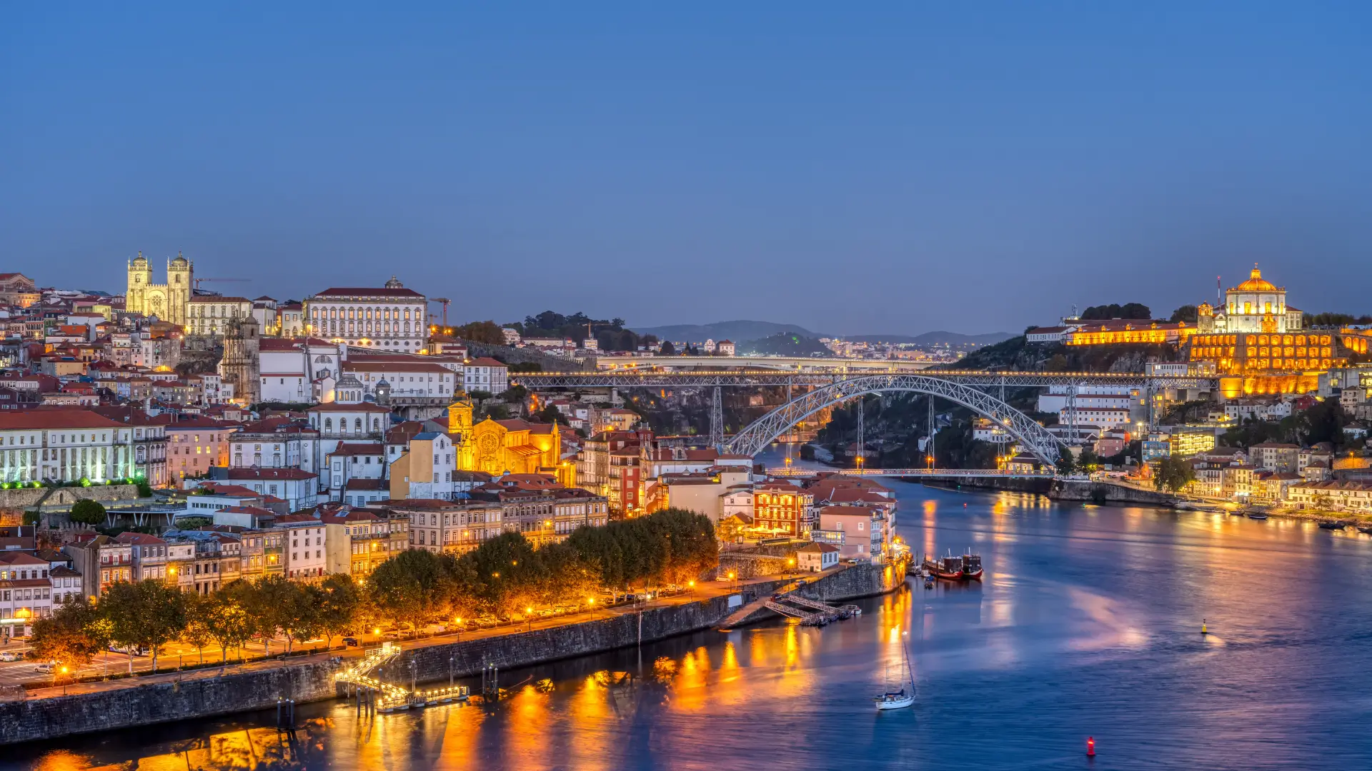 Dom Luís I Bridge over the Douro River with Porto and Vila Nova de Gaia illuminated at night.