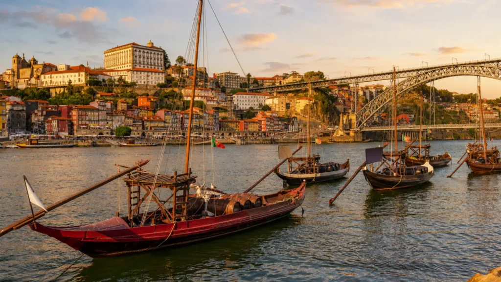 Rabelo boats on the Douro River with Porto's Ribeira and Dom Luís I Bridge.
