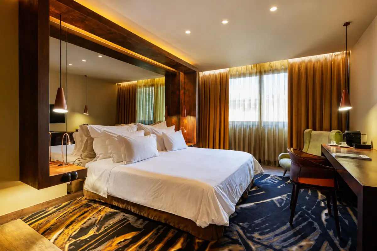Guest room at PortoBay Hotel Teatro with a large bed, desk and warm interior lighting.