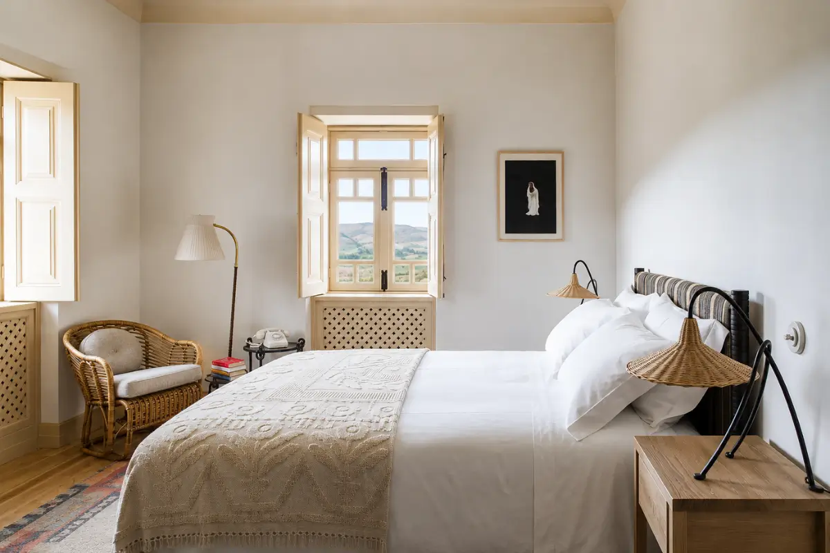Bright bedroom with wicker lighting and vineyard views at Quinta da Côrte.