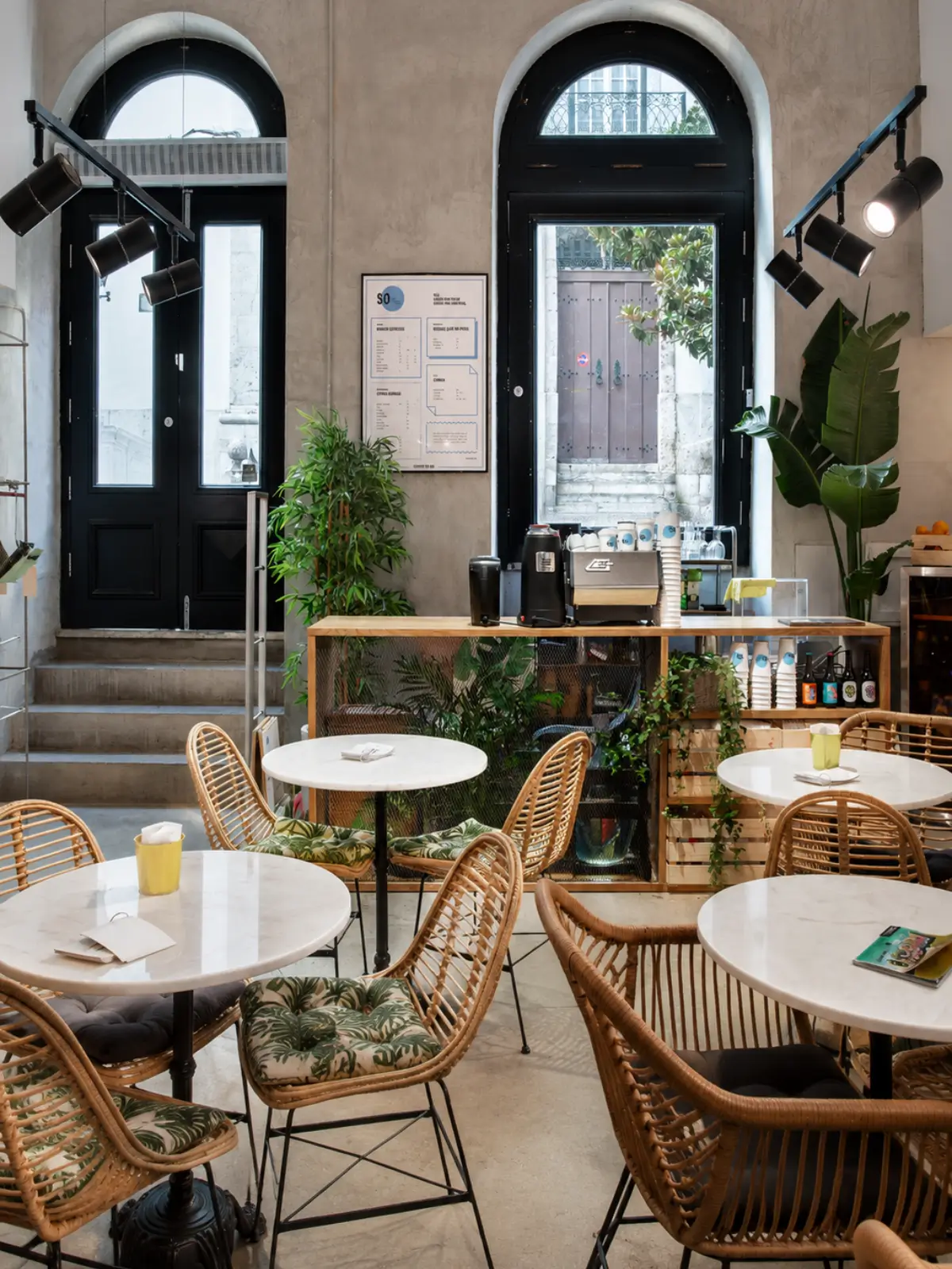 Interior of SO Coffee Roasters in Porto with café tables, rattan chairs and the coffee counter.