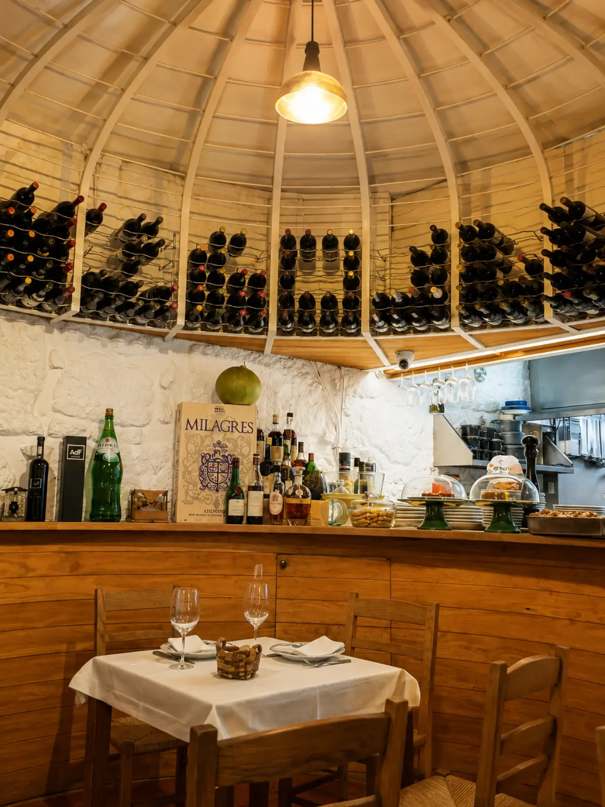Dining room at Taberna dos Mercadores with wine bottles displayed above the tables.