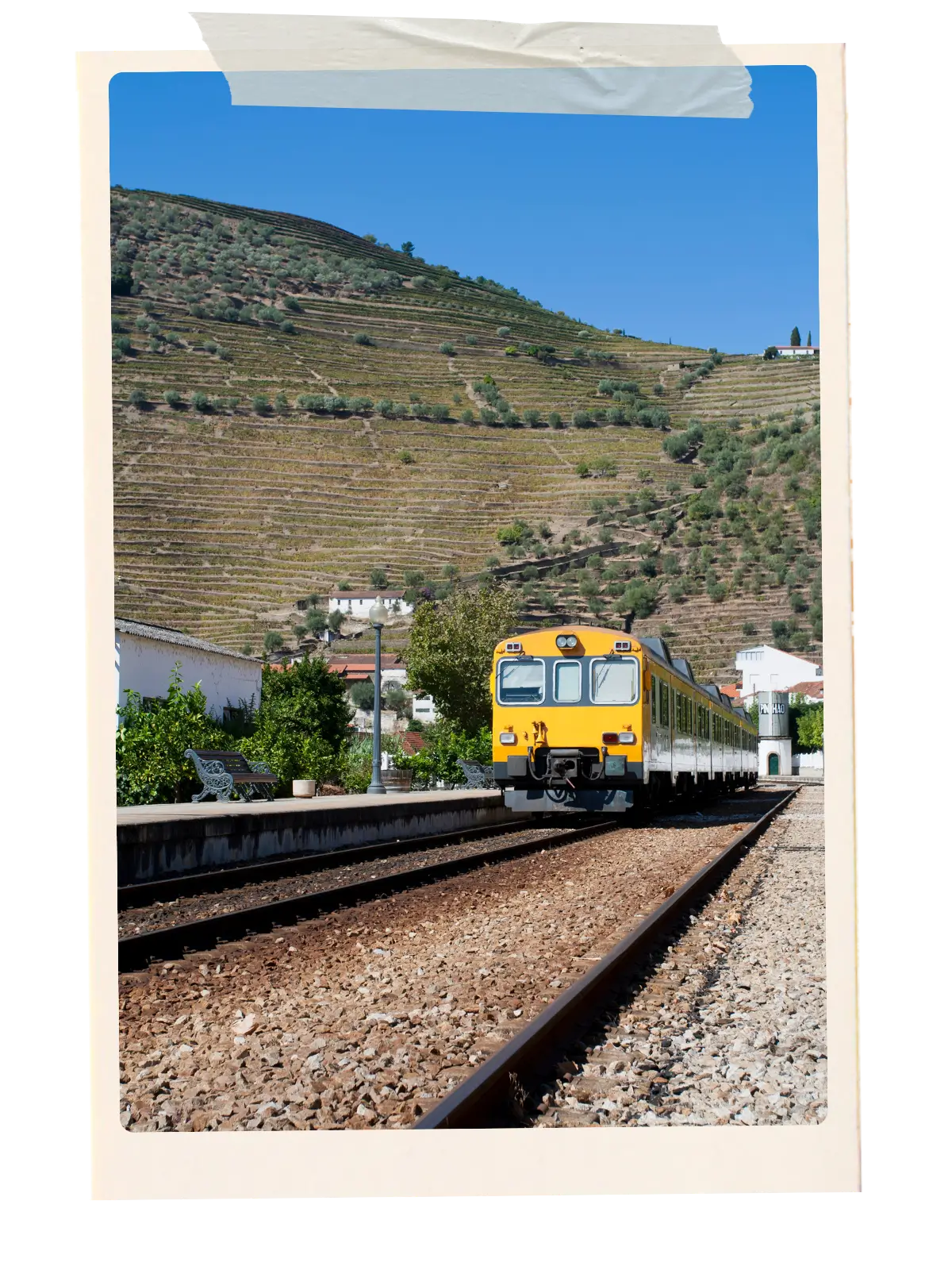 Train at Pinhão station with terraced vineyards behind it.