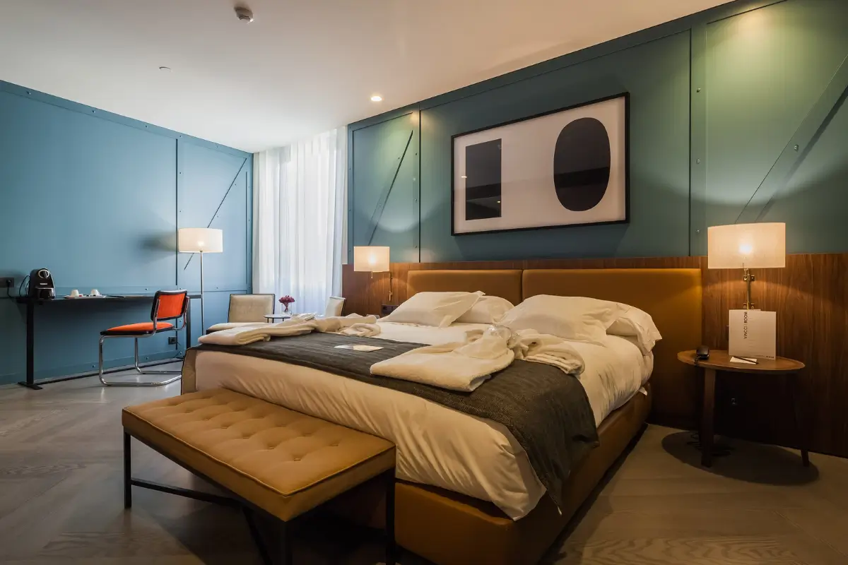 Modern room at Vincci Ponte de Ferro in Porto with teal walls, warm wood accents and a large bed.