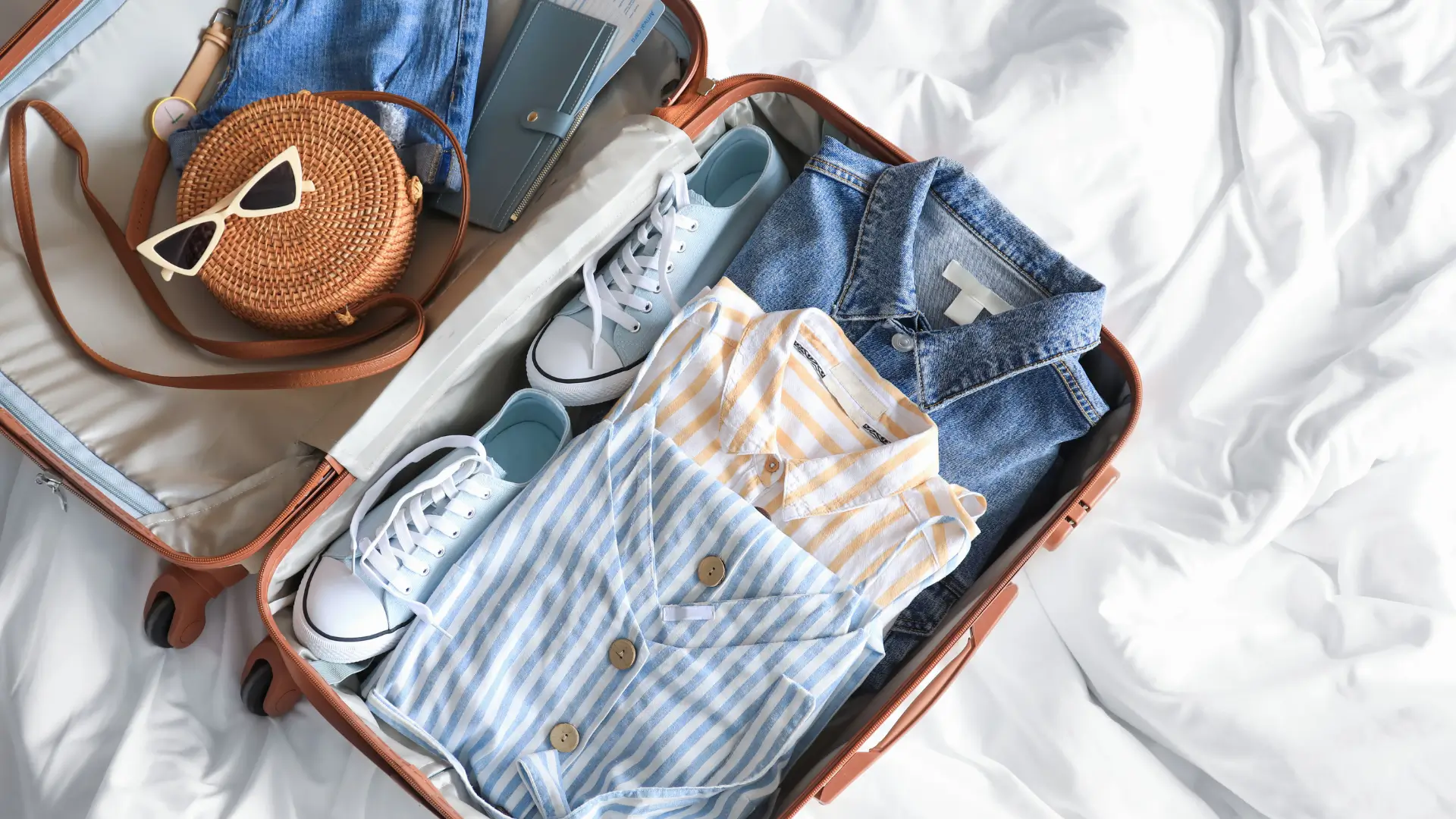 Open carry-on suitcase packed with clothes and shoes.