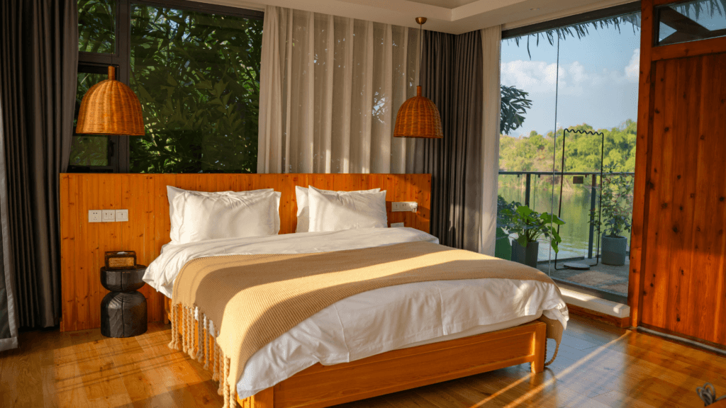Travel accommodation with a double bed and balcony overlooking the water.