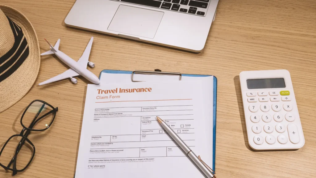 Travel insurance claim form on a desk with a model plane and calculator.